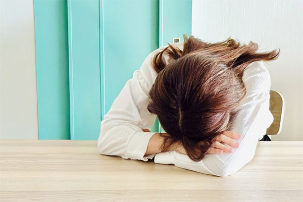 机に突っ伏す女性